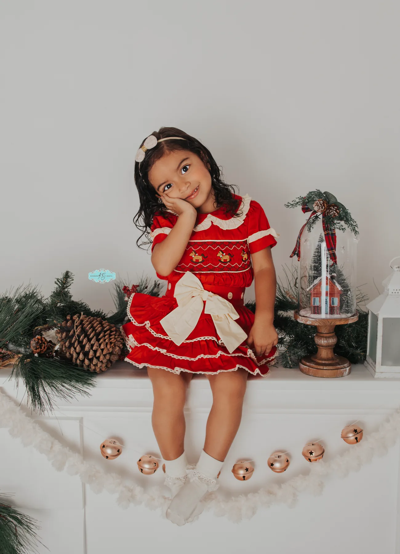 Girl in a red Christmas dress sitting on a decorated mantel