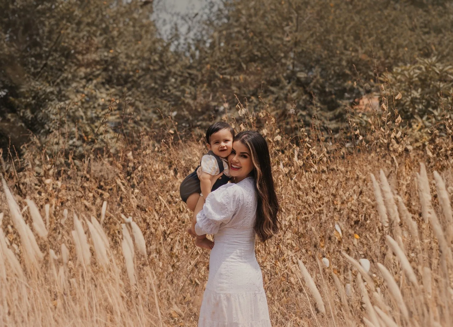 mother holding her baby in golden fall grass during a family session near Orlando